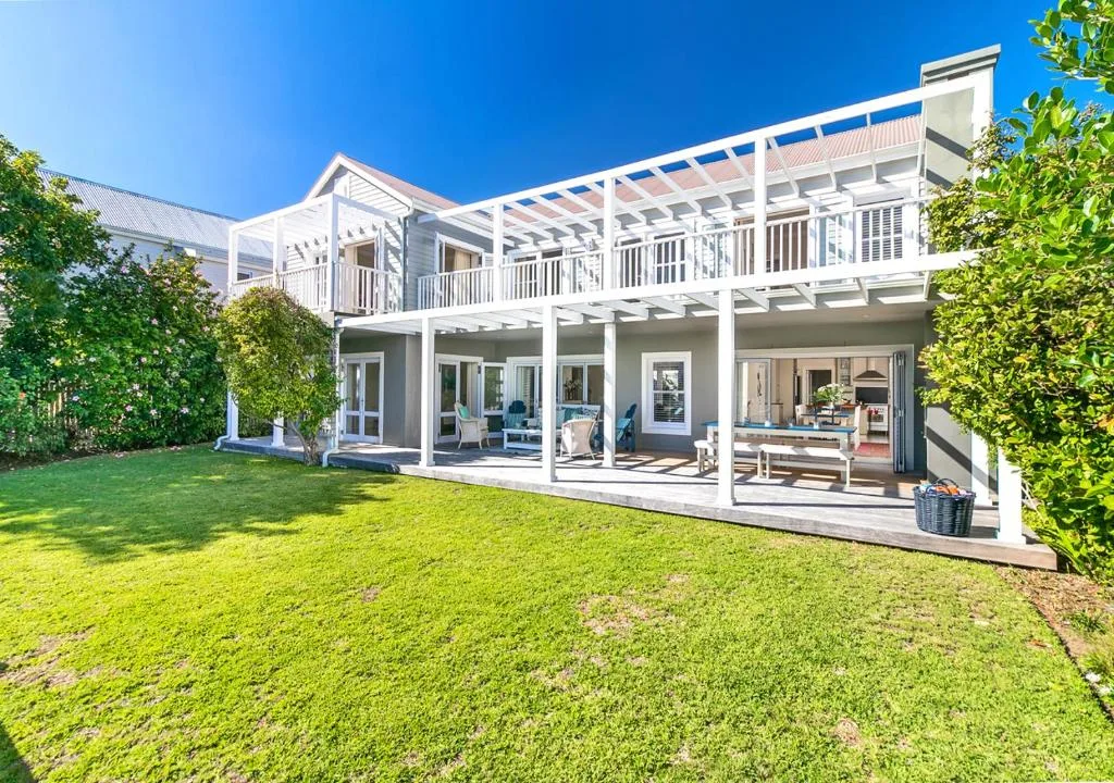 White modern house with deck and manicured lawn, clear sky