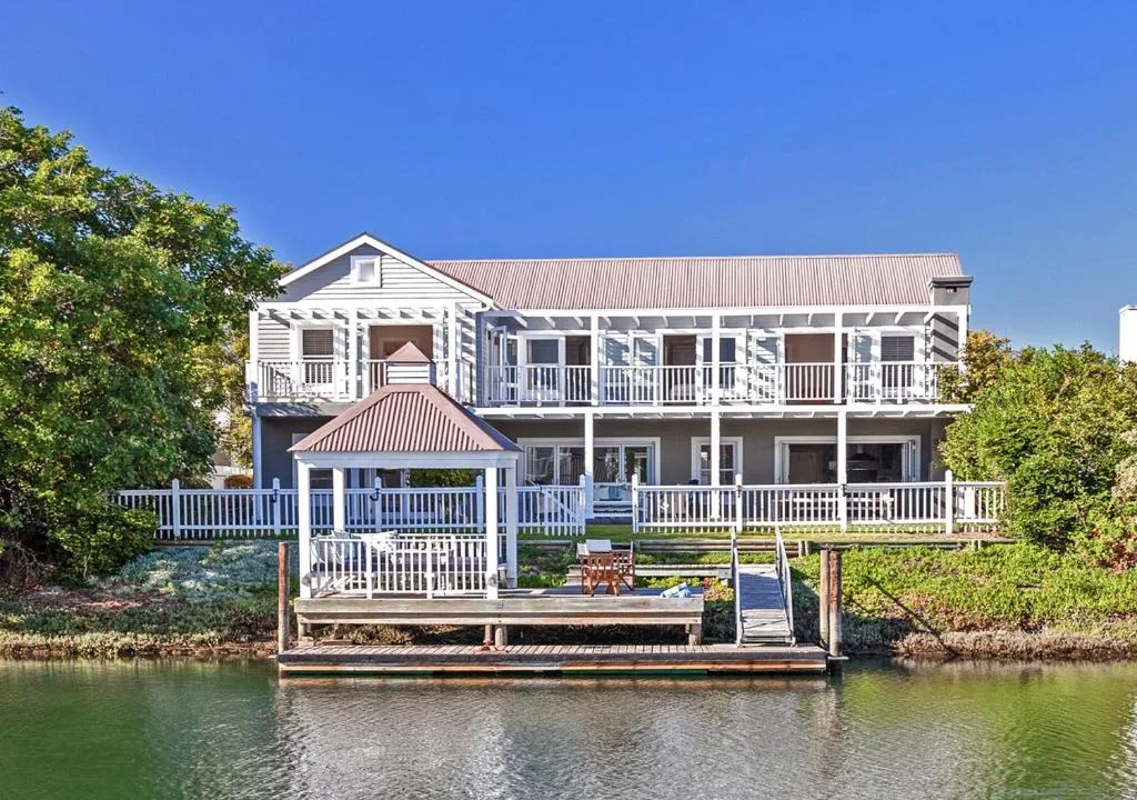 Waterfront holiday home with white railings and red metal roof