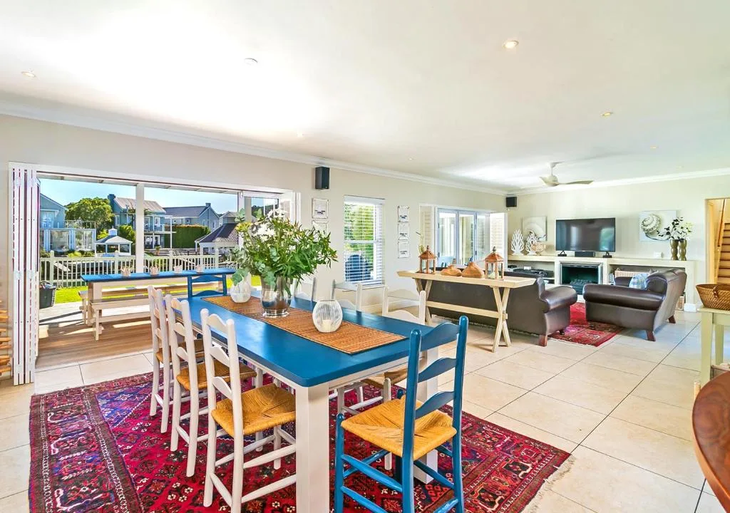 Open-plan living area with dining table, lounge seating, and canal views through large windows