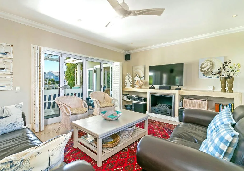 Bright living room with leather sofas, TV, fireplace, and deck access