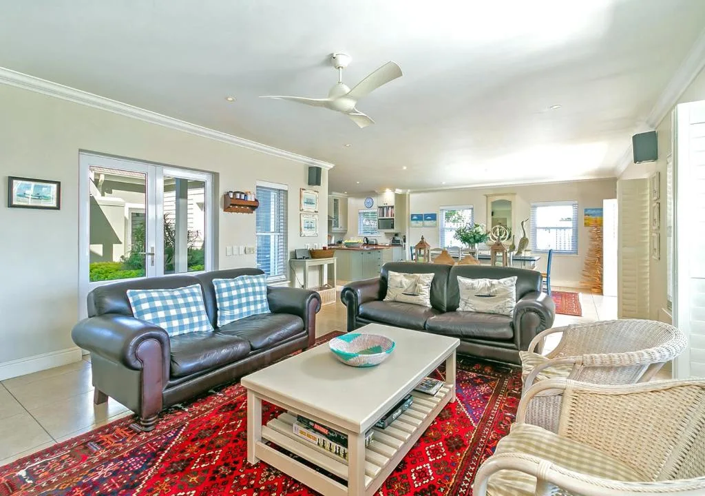 Spacious open-plan lounge with leather sofas and wicker chairs overlooking garden