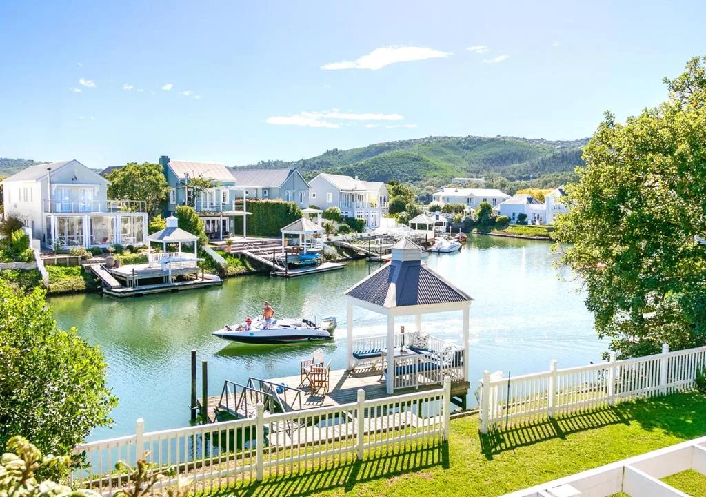 Scenic lagoon view with gazebo, boats, and colorful waterfront homes beyond