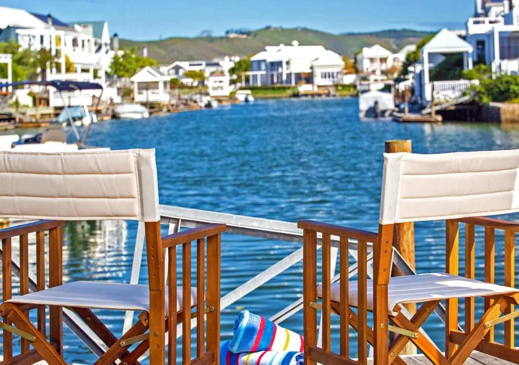 Waterfront view from deck with boats and colorful houses across lagoon