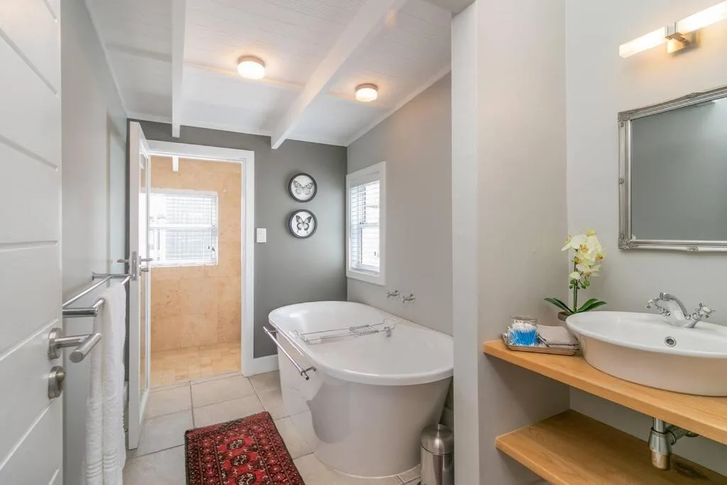 Modern bathroom with freestanding soaking tub, round white basin sink, and wooden vanity