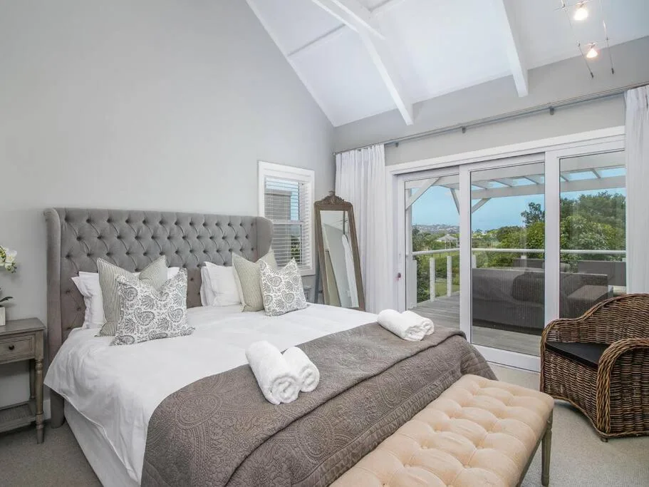 Bright bedroom with gray tufted headboard and garden view doors