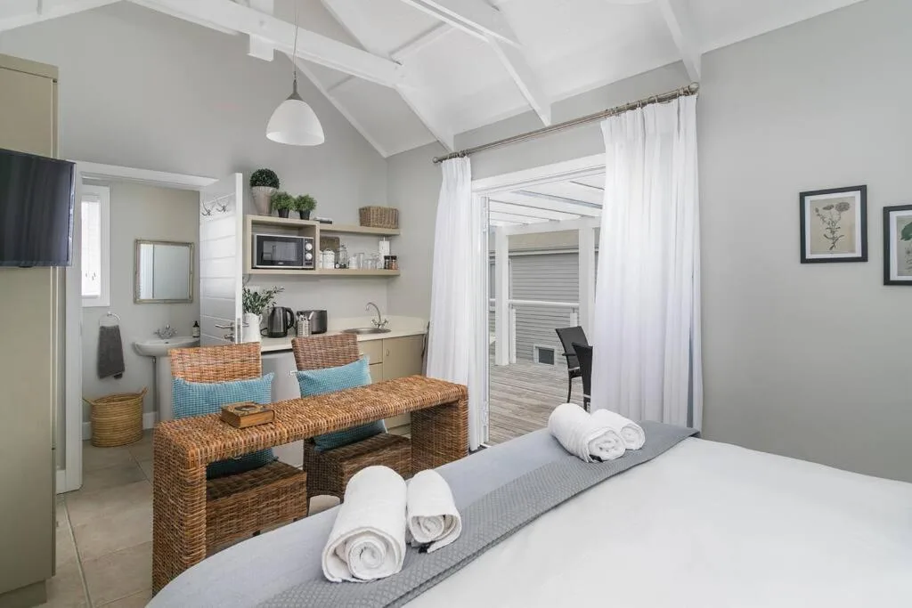 Bright bedroom with bed, kitchenette, and deck access through glass doors