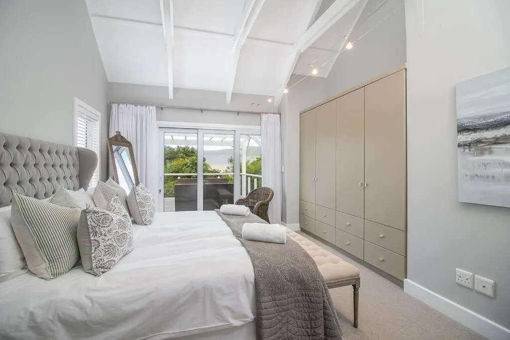 Spacious bedroom with king bed, water views through glass doors, and built-in wardrobe
