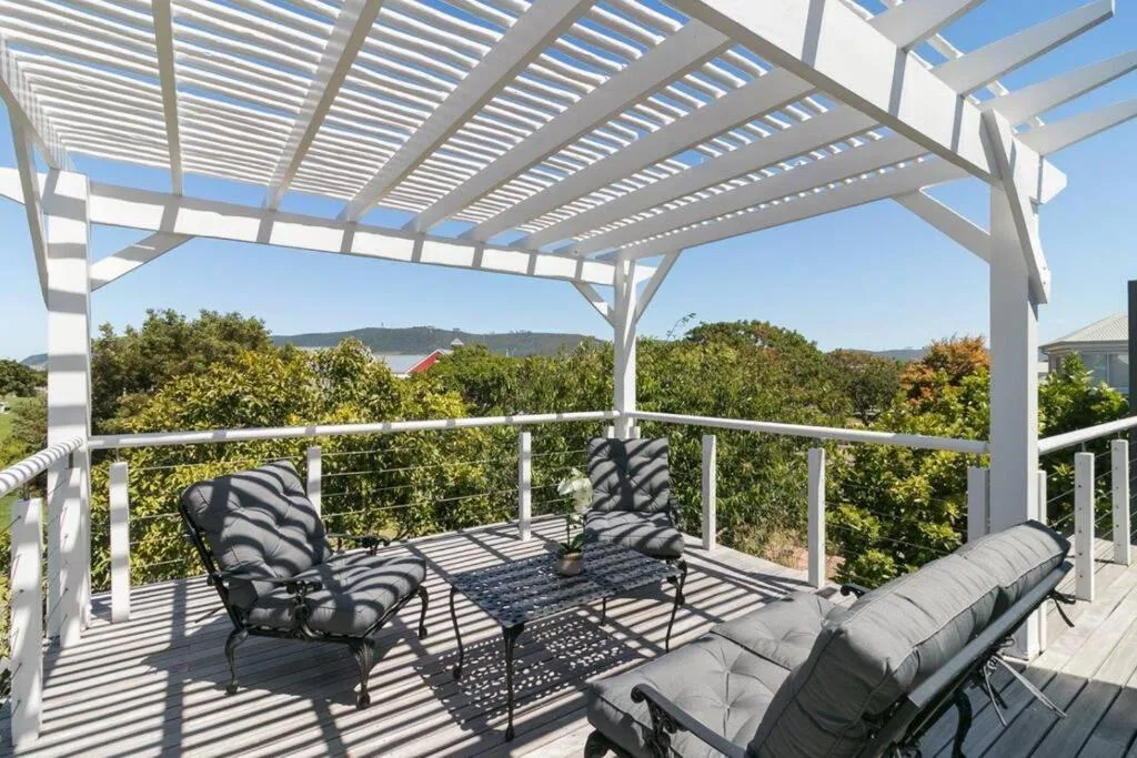 Shaded deck with lounge chairs overlooking Knysna lagoon and forested hills