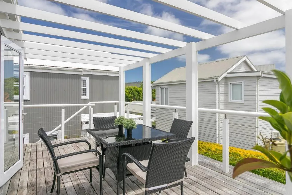 Covered outdoor dining area with table, chairs, and garden views