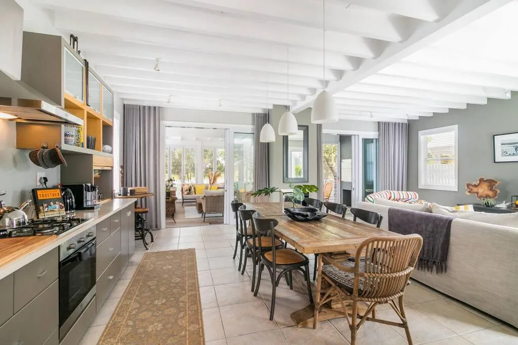 Open-plan dining area with wooden table and woven chairs, connecting to kitchen