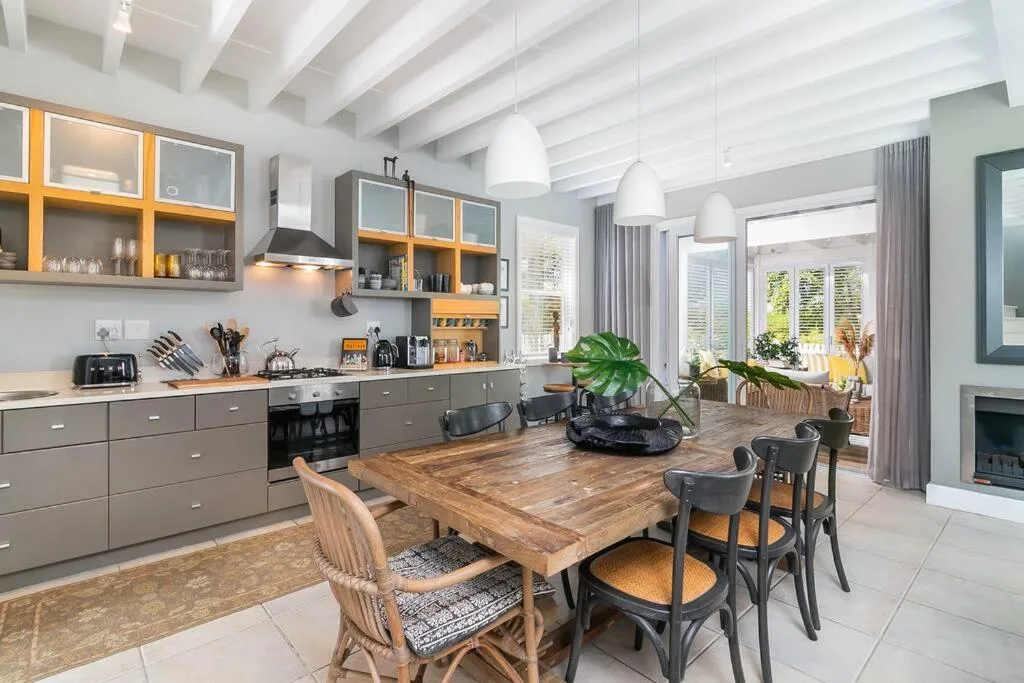 Open-plan dining area with wooden table and black chairs, modern kitchen visible