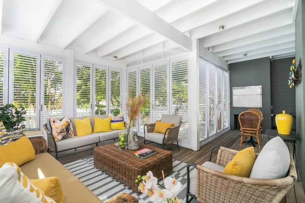 Bright lounge with yellow accents, rattan furniture, and garden views