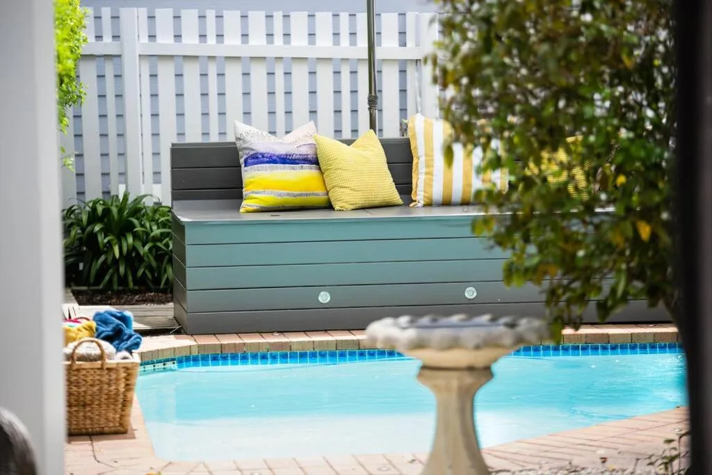 Turquoise swimming pool with colorful cushioned bench seating nearby