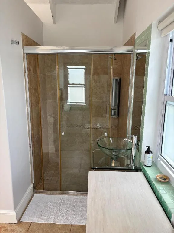 Modern bathroom with walk-in shower, glass enclosure, and round sink