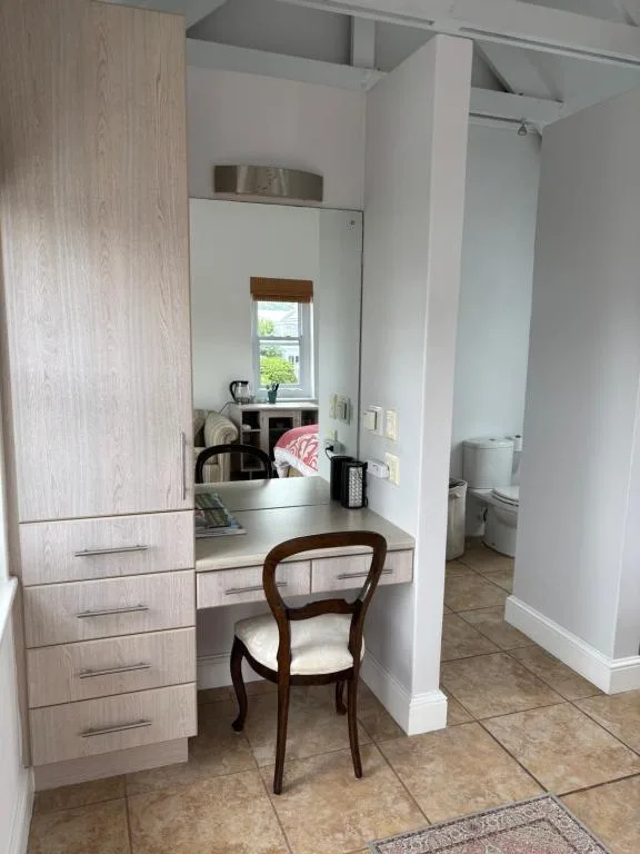 Bathroom vanity with mirror, wooden cabinetry, and chair seating area