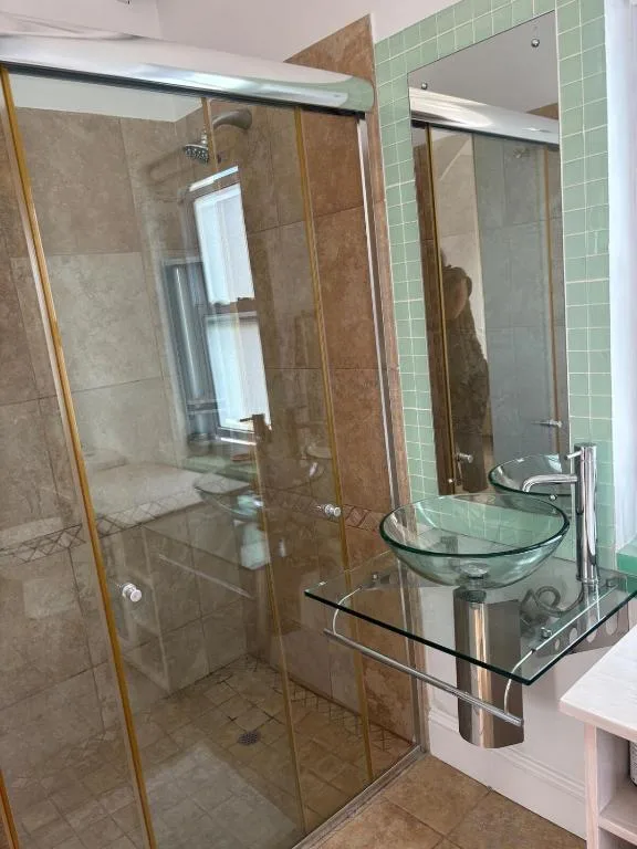 Modern bathroom with glass shower enclosure and green tiled walls