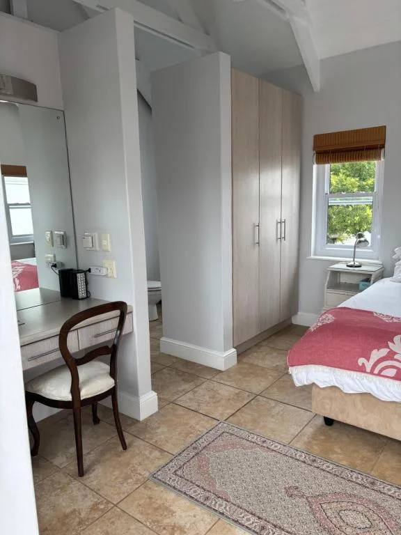 Bright bedroom with double bed, vanity desk, wardrobe, and window view