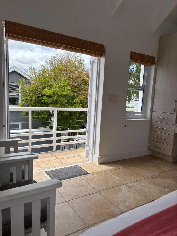 Open glass doors leading to a spacious balcony with white railings and garden views
