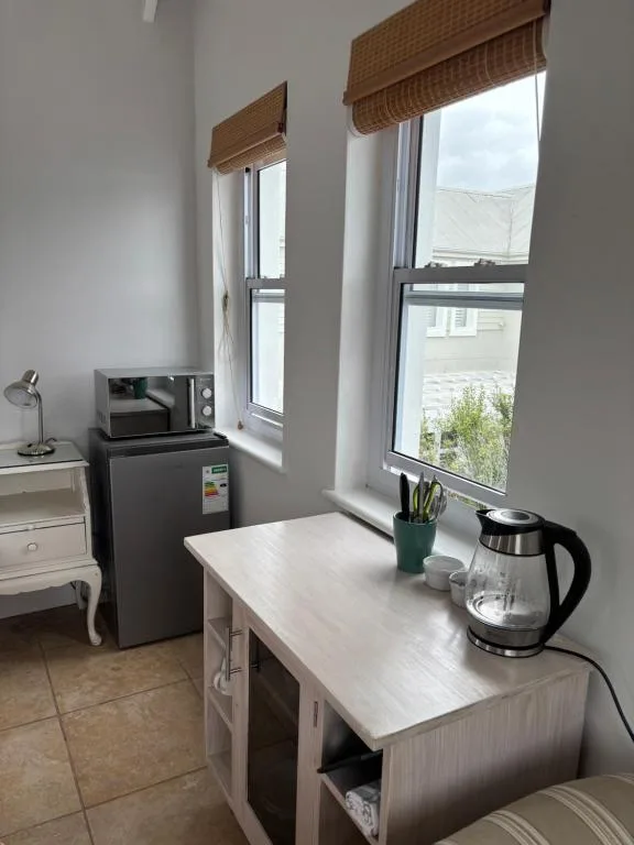 Compact kitchenette with microwave, fridge, kettle and window views