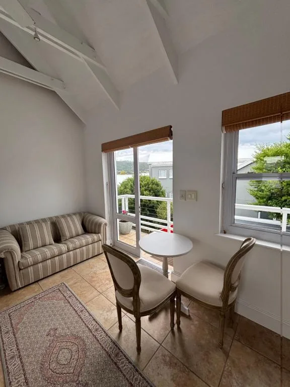 Bright lounge area with striped sofa, round table, and garden views through glass doors