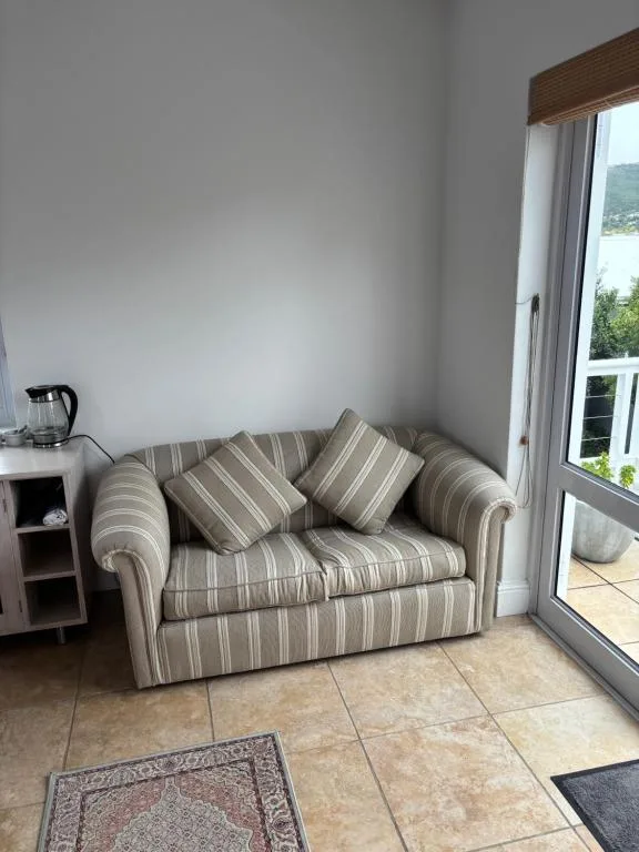 Striped upholstered loveseat with cushions beside glass doors