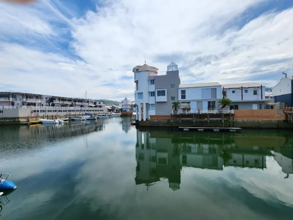 Waterfront apartments with boats reflected in calm lagoon water
