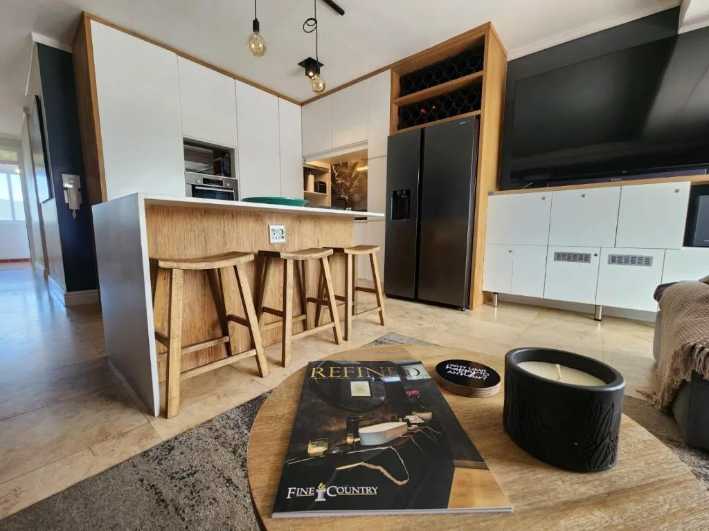 Modern open-plan kitchen with wooden island, bar seating, and black appliances