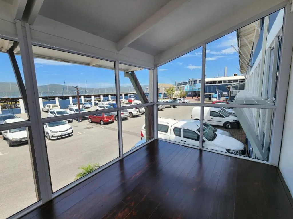 Waterfront harbor views through large windows with boats and mountains