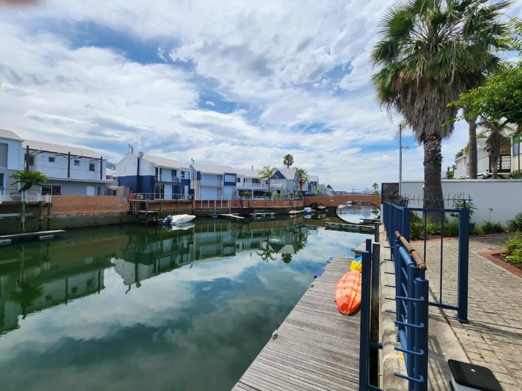 Waterfront canal with moored boats, palm trees, and modern residential buildings