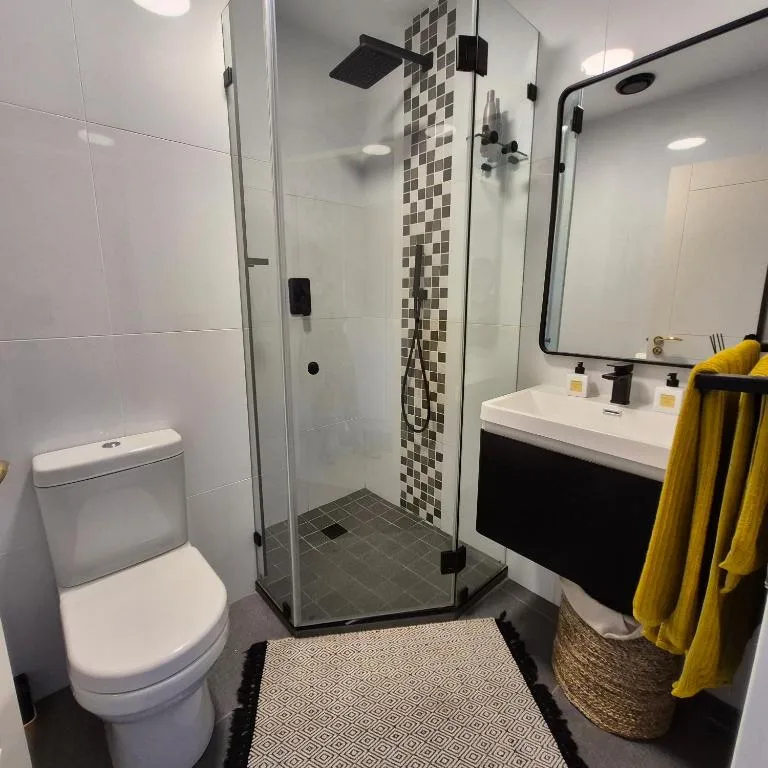 Modern bathroom with walk-in shower, toilet, vanity sink and mirror