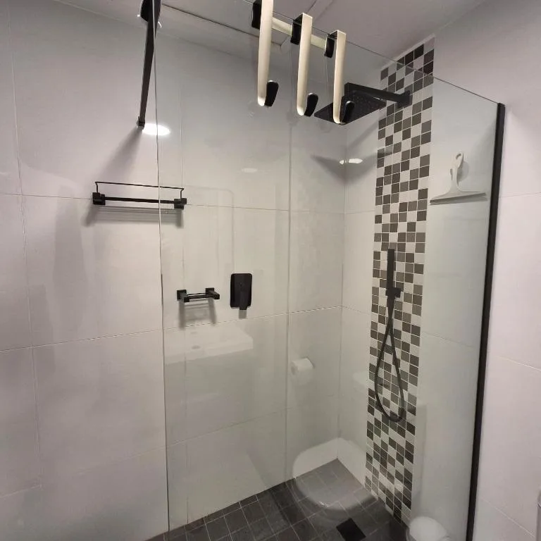 Modern shower enclosure with black hardware and geometric tile accent