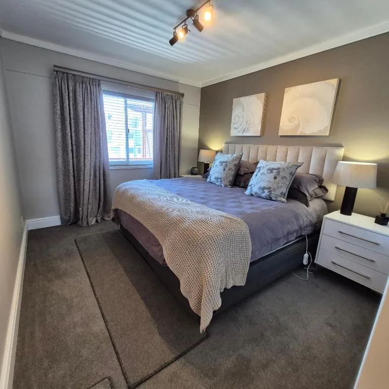 Spacious master bedroom with queen bed, neutral decor, and natural light from windows