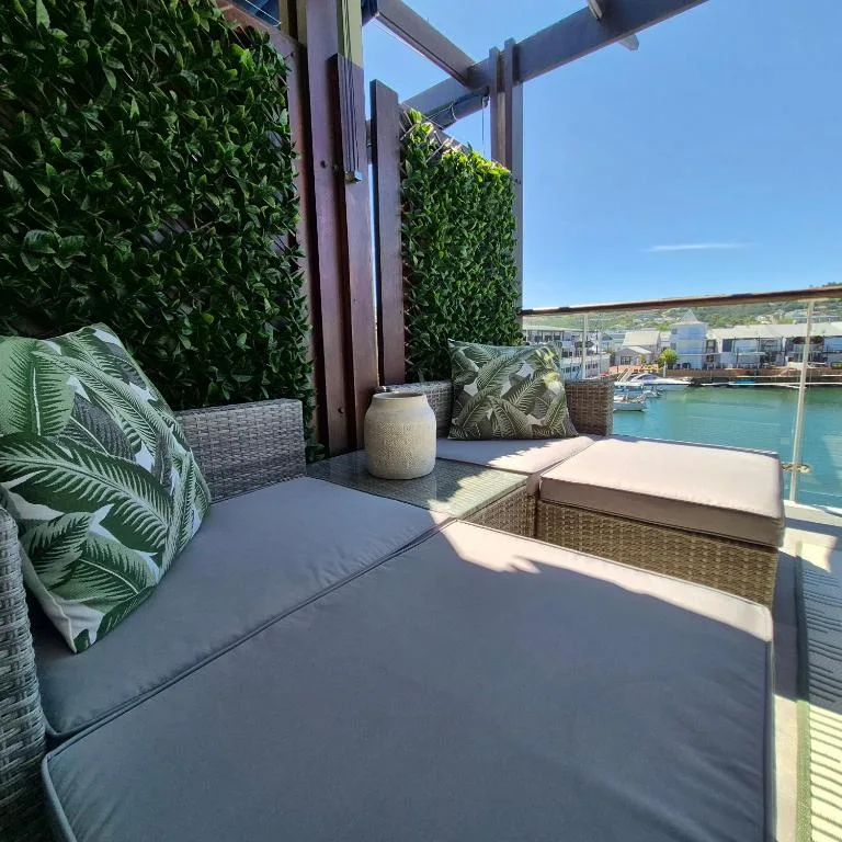 Shaded deck with woven furniture overlooking Knysna Lagoon and marina