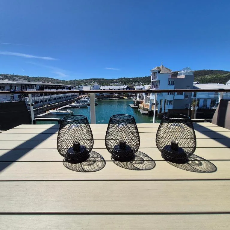 Three modern chairs on a waterfront deck overlooking Knysna harbor