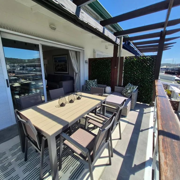 Spacious outdoor patio with dining table, chairs, and harbor views