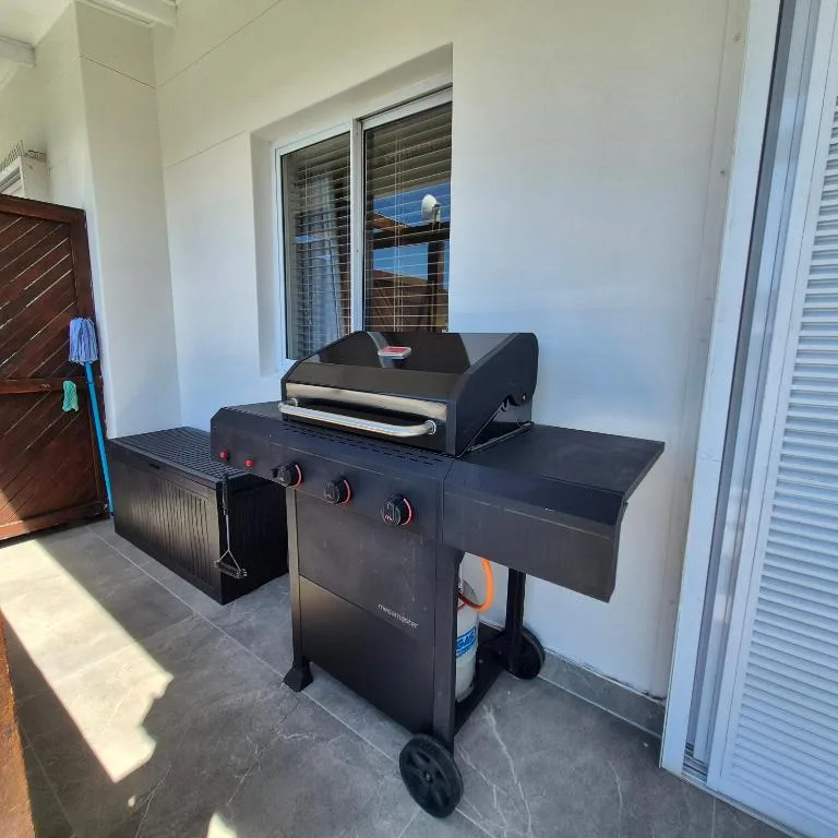 Outdoor braai grill on covered patio with ocean views through doors