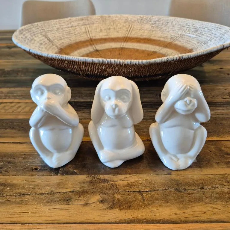 White ceramic monkey figurines and woven basket on wooden table