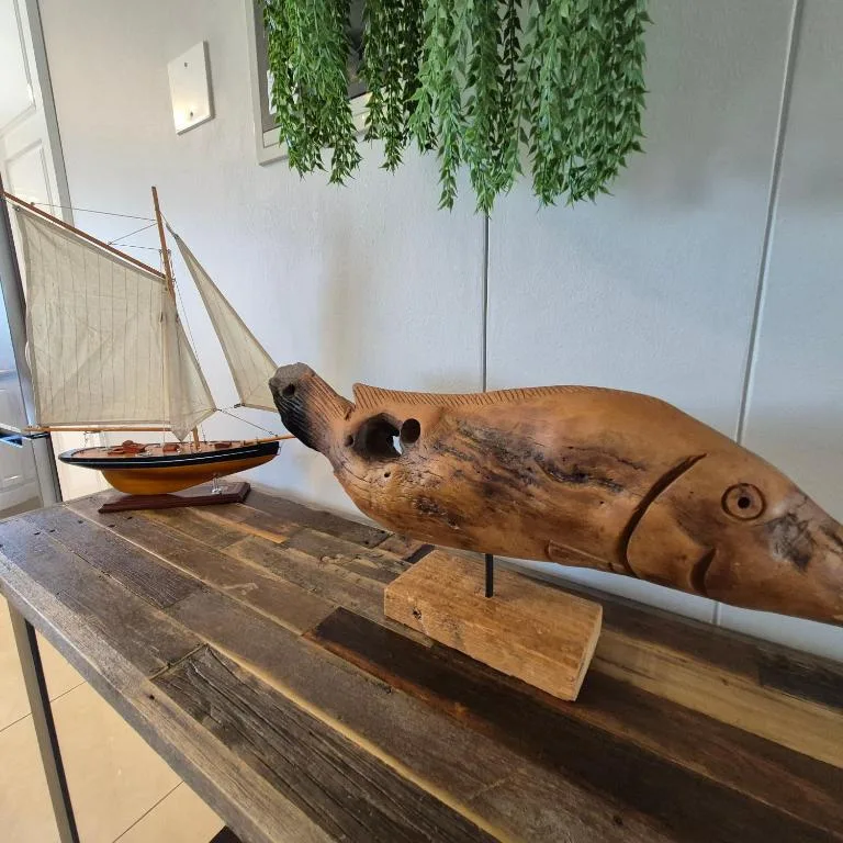 Wooden fish sculpture and sailboat model on rustic shelf display