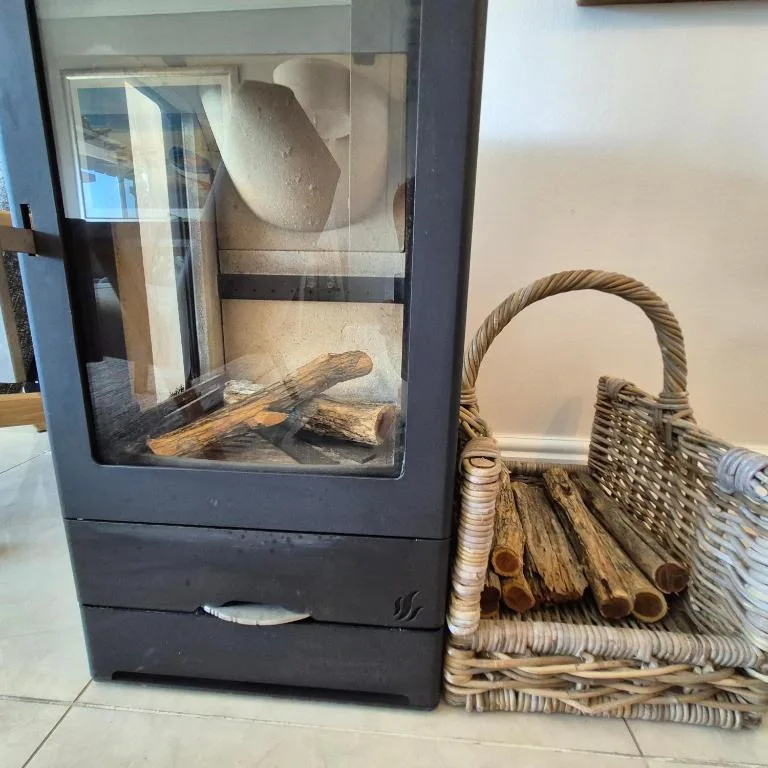 Wood-burning stove with firewood and woven basket for logs