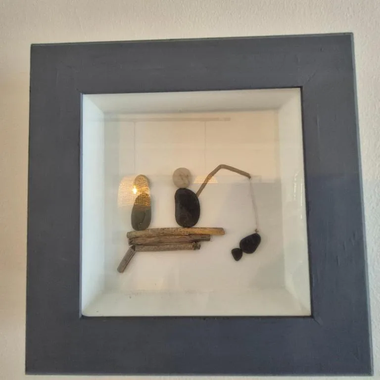 Framed wall art with shells and driftwood arranged on white background