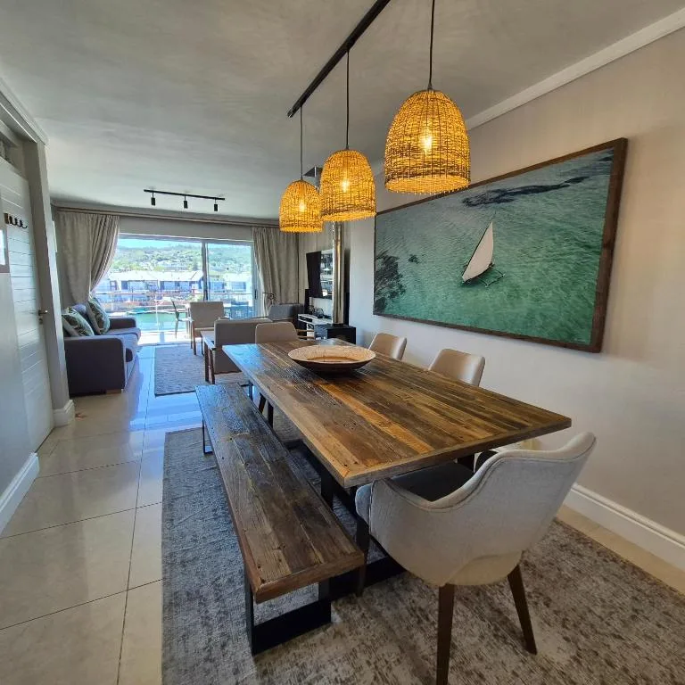 Modern dining area with wooden table and rattan pendant lights overlooking Knysna Heads