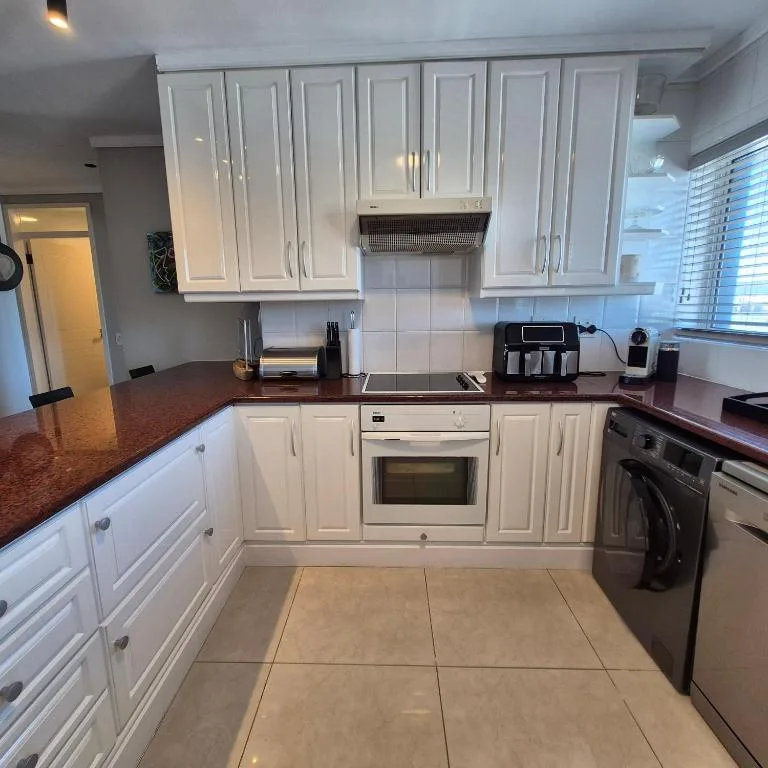 Modern kitchen with white cabinetry, dark countertops, and stainless steel appliances
