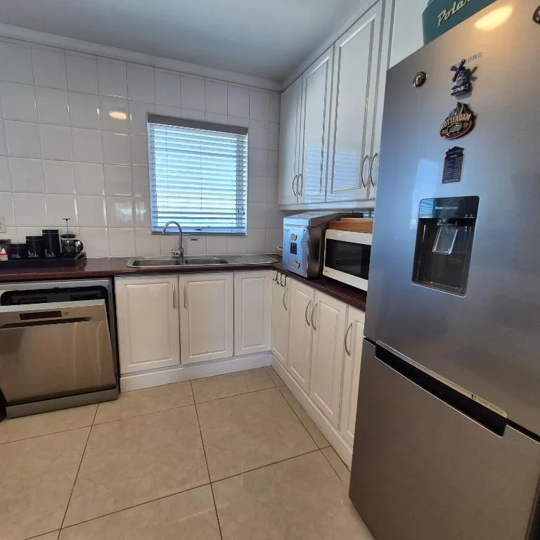 Modern kitchen with white cabinetry, stainless steel appliances, and tiled flooring