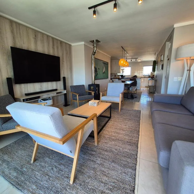 Modern lounge with TV, sofas, and open-plan kitchen view
