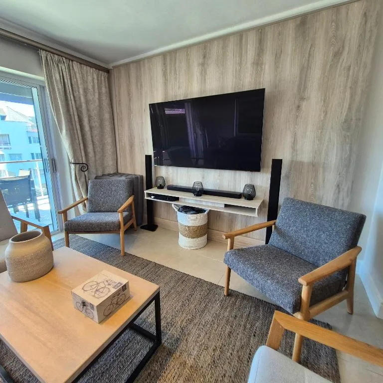 Modern living room with wall-mounted TV, comfortable seating, and coastal views