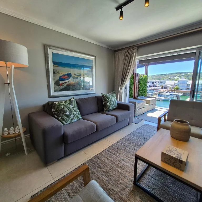 Modern lounge with dark sofa, ocean view through sliding doors, artwork
