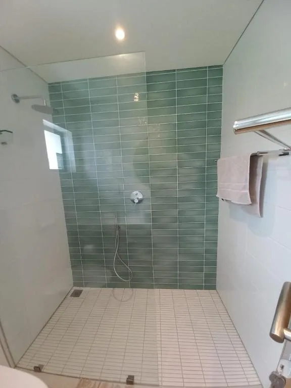 Modern bathroom with green tile shower enclosure and white floor tiles