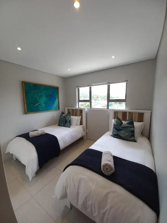 Twin bedroom with two single beds, ocean artwork, and bright windows overlooking lagoon