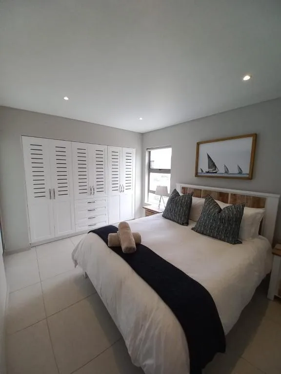 Bright bedroom with queen bed, white built-in wardrobes, nautical artwork