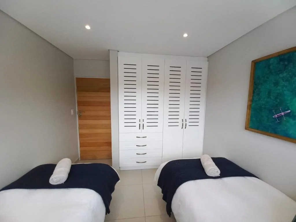 Twin bedroom with two single beds, white storage wardrobe, and modern lighting